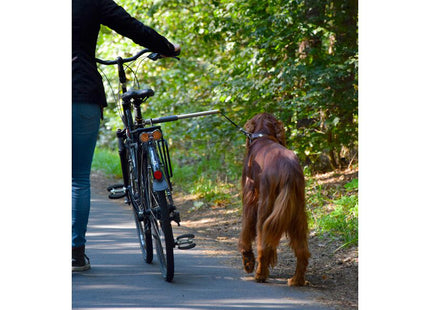 Een vrouw fietst met een hond aangelijnd met behulp van de Camon - Walky Dog Fietsbeugel.