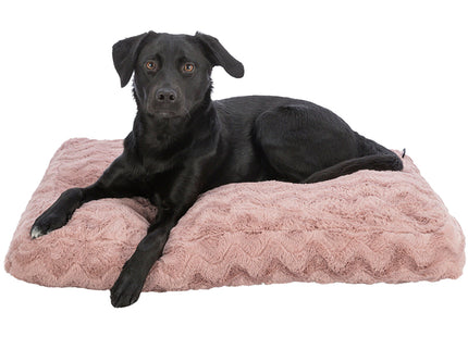 Een zwarte hond ligt comfortabel te loungen op een roze Trixie Hondenkussen Loki 