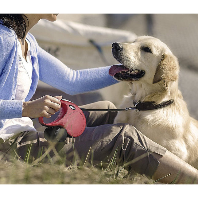 Een vrouw gebruikt een Flexi - Rollijn Classic L - Tape Leash om een hond te aaien.