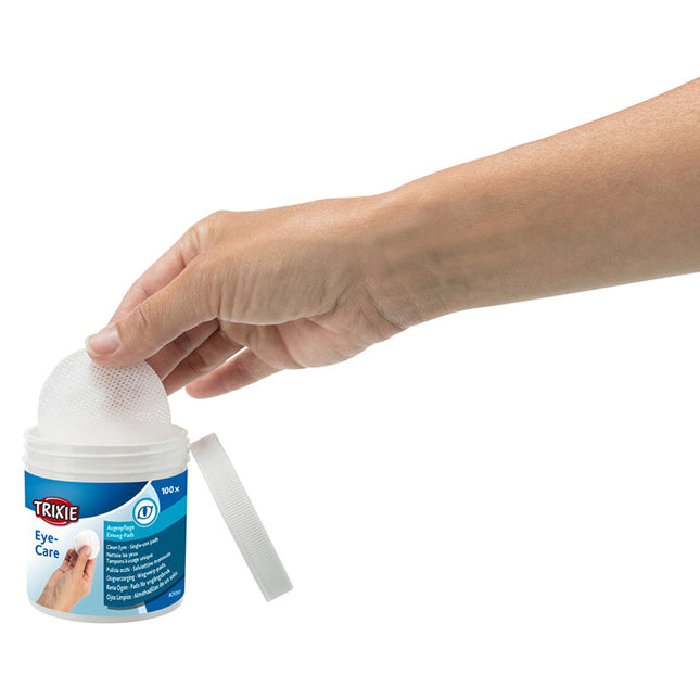 Een hand houdt een bakje handdesinfecterend middel vast terwijl Trixie - Oogzorgpads worden gebruikt.