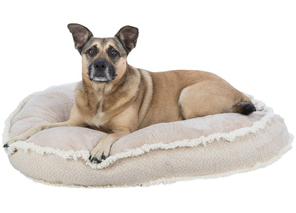 Een bruine hond liggend op een beige Trixie - Hondenkussen Boho met een slipvaste onderkant.