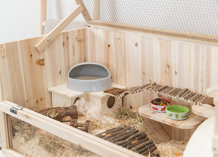 Een Trixie - Knaagdierenverblijf houten hamsterkooi met voer en speelgoed erin.